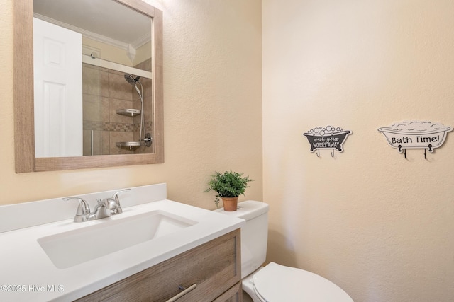 bathroom featuring vanity, crown molding, a shower with shower door, and toilet