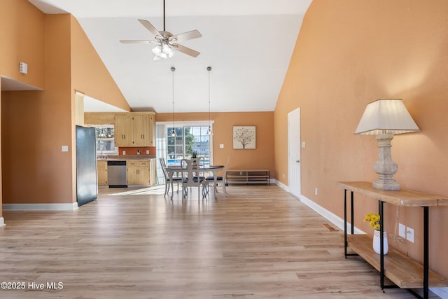 dining space with light hardwood / wood-style flooring, high vaulted ceiling, and ceiling fan