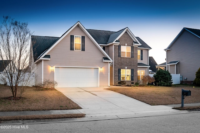 traditional-style home featuring a garage, concrete driveway, brick siding, and fence