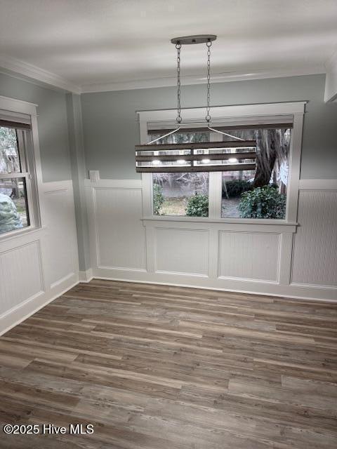 unfurnished dining area with ornamental molding, dark wood-style flooring, and wainscoting