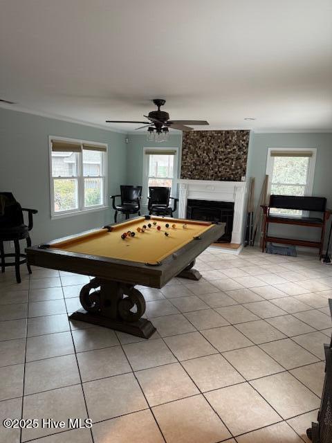 playroom with light tile patterned floors, plenty of natural light, a fireplace with raised hearth, and crown molding