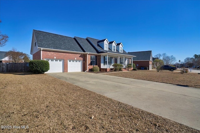 cape cod home featuring a garage, a front yard, and a porch