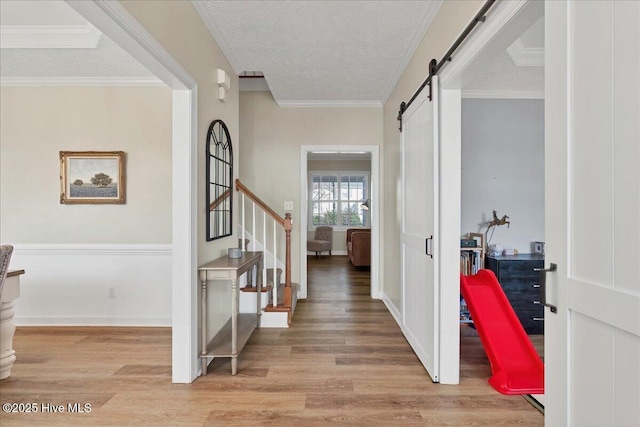 entrance foyer featuring crown molding, a barn door, light hardwood / wood-style flooring, and a textured ceiling