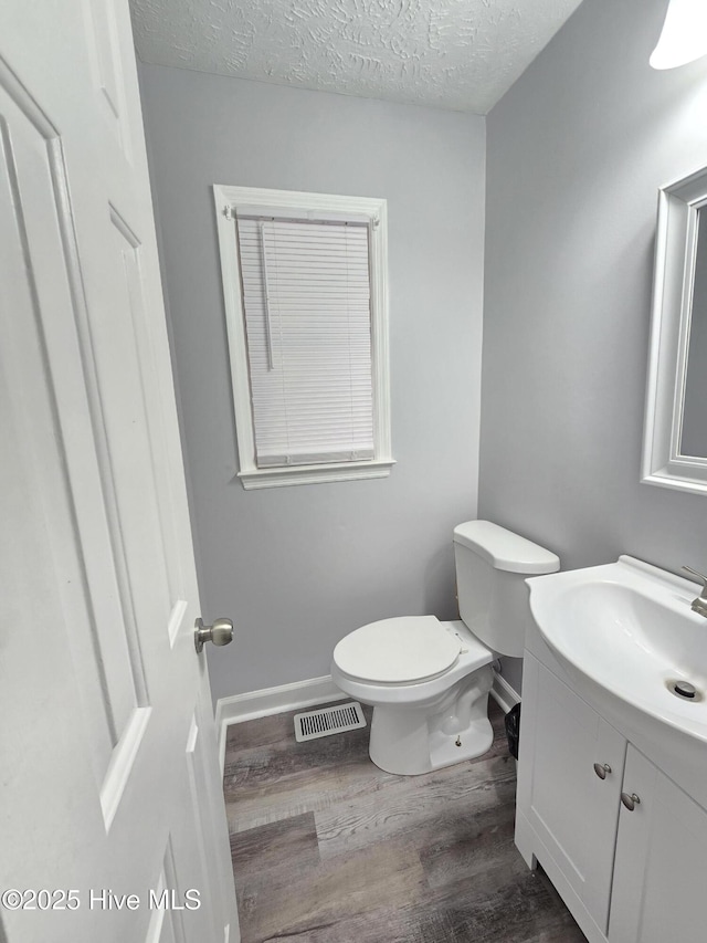 bathroom featuring vanity, hardwood / wood-style floors, a textured ceiling, and toilet