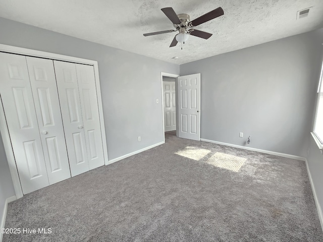 unfurnished bedroom featuring ceiling fan, carpet, a textured ceiling, and a closet