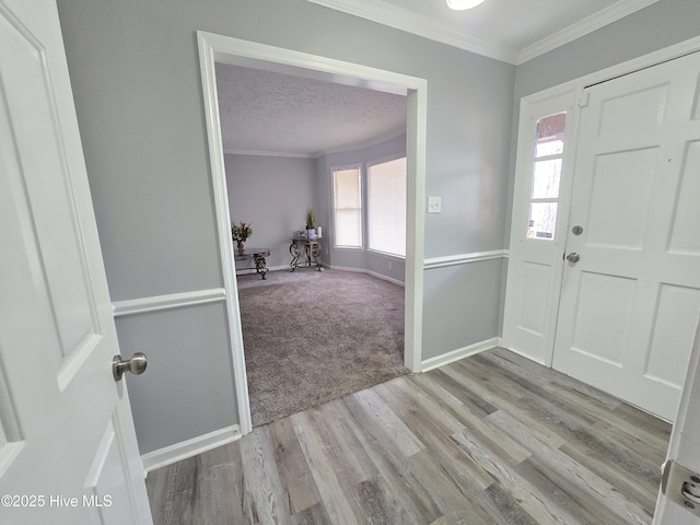 foyer entrance with crown molding, a textured ceiling, and light wood-type flooring