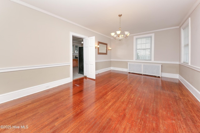 spare room with ornamental molding, baseboards, radiator heating unit, and wood finished floors