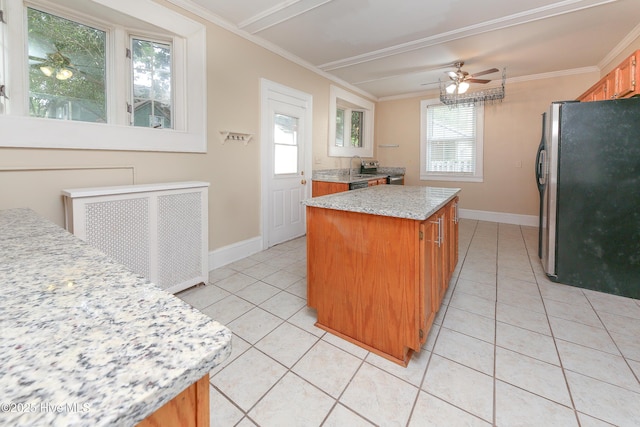 kitchen with ornamental molding, light tile patterned flooring, freestanding refrigerator, and a center island