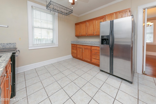 kitchen with light tile patterned flooring, light countertops, plenty of natural light, stainless steel fridge, and crown molding