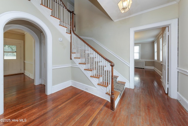 stairs with ornamental molding, radiator heating unit, wood finished floors, and baseboards