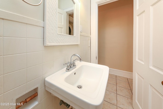 bathroom with tile patterned flooring, a sink, tile walls, and baseboards