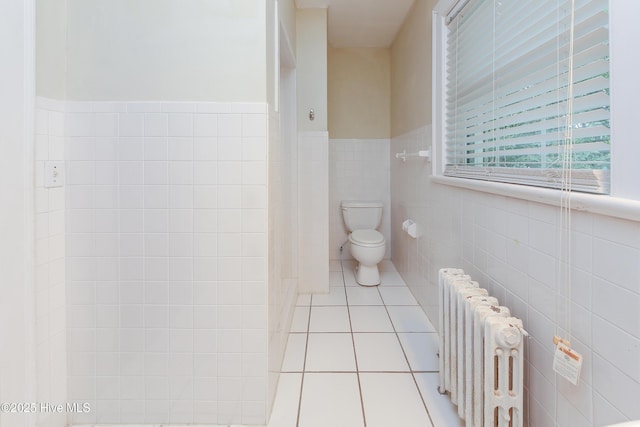 bathroom with a wainscoted wall, tile walls, radiator, toilet, and tile patterned floors