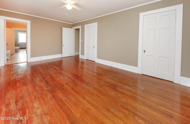 unfurnished bedroom with ornamental molding, radiator heating unit, wood finished floors, and baseboards