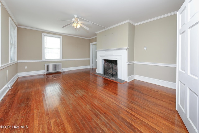 unfurnished living room featuring radiator, a fireplace, crown molding, and wood finished floors