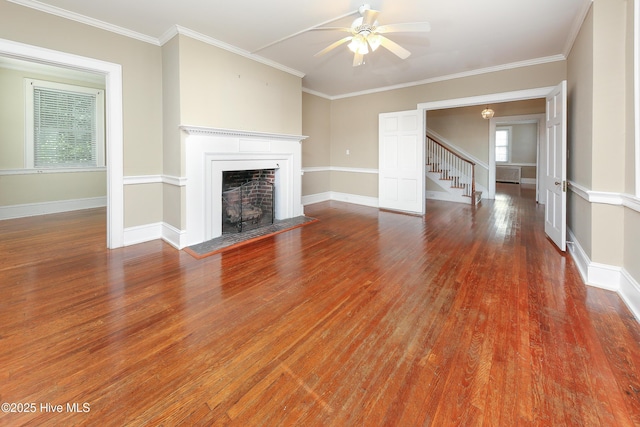 unfurnished living room with baseboards, a fireplace with flush hearth, ornamental molding, and wood finished floors