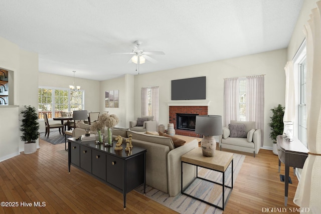 1652 Chadwick Shores Dr, Sneads Ferry, NC 28460 - living room with a ceiling fan, light wood-style flooring, a fireplace, a chandelier, and baseboards