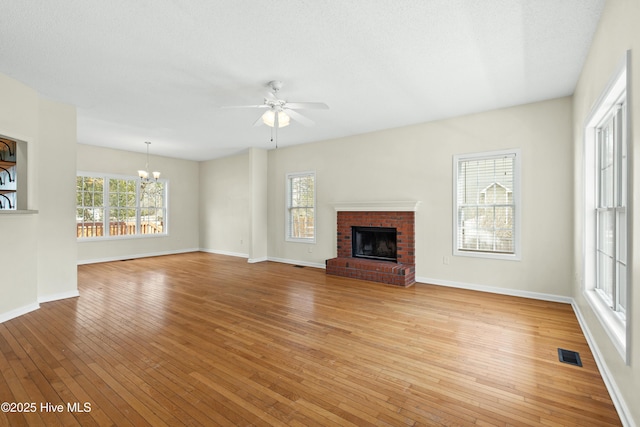 1652 Chadwick Shores Dr, Sneads Ferry, NC 28460 - unfurnished living room with a chandelier, light wood-style floors, ceiling fan, a brick fireplace, and baseboards