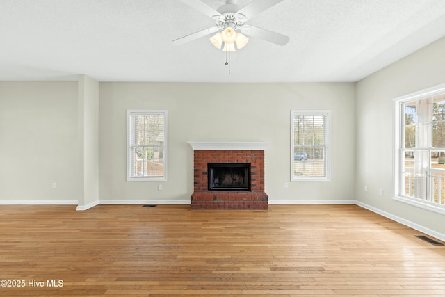 1652 Chadwick Shores Dr, Sneads Ferry, NC 28460 - unfurnished living room featuring light wood-type flooring, healthy amount of natural light, a fireplace, baseboards, and a textured ceiling