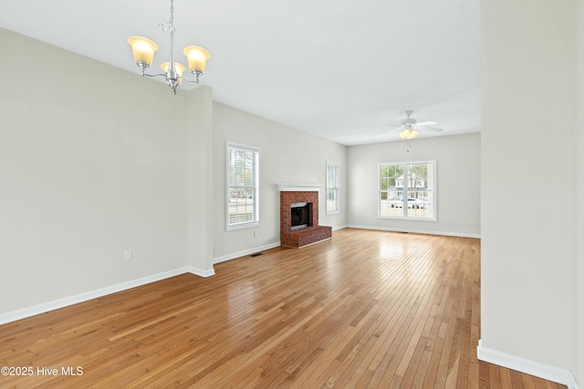 1652 Chadwick Shores Dr, Sneads Ferry, NC 28460 - unfurnished living room featuring a chandelier, light wood-style flooring, ceiling fan, a brick fireplace, and baseboards