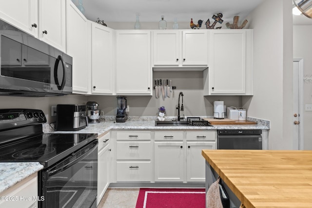 kitchen with white cabinetry, sink, light stone counters, and black appliances