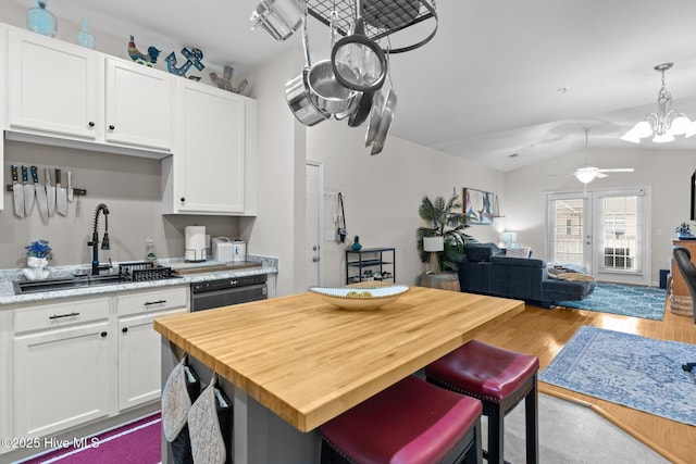 kitchen featuring lofted ceiling, sink, white cabinetry, dishwasher, and a kitchen island