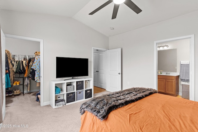 carpeted bedroom with lofted ceiling, a walk in closet, ensuite bath, a closet, and ceiling fan