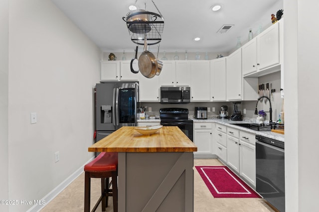 kitchen featuring a center island, butcher block counters, white cabinets, and black appliances