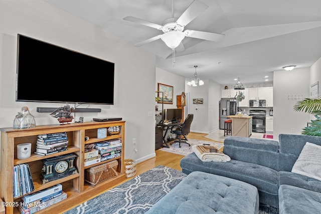 living room with ceiling fan with notable chandelier and light hardwood / wood-style flooring