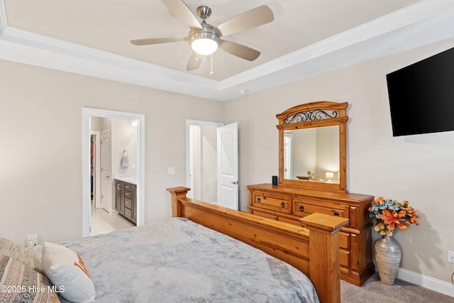 carpeted bedroom with ensuite bath, a raised ceiling, and ceiling fan