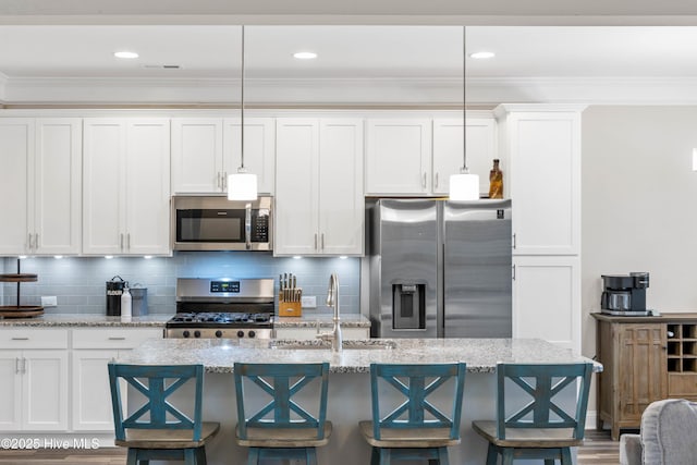 kitchen featuring hanging light fixtures, appliances with stainless steel finishes, and white cabinets