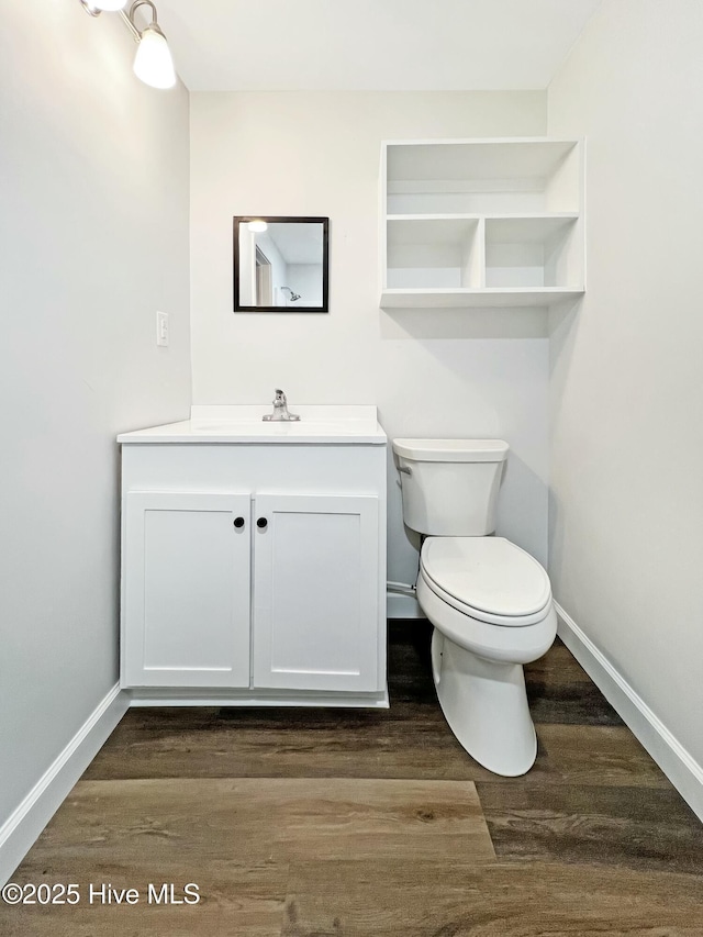 bathroom featuring wood-type flooring, toilet, and vanity