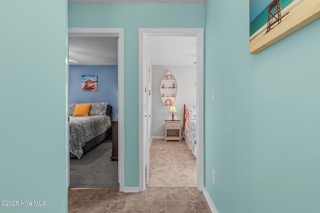 corridor with carpet and a textured ceiling