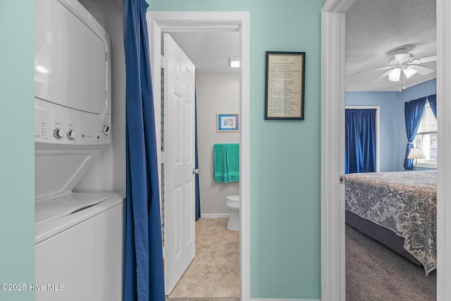 laundry room with ceiling fan, stacked washer and clothes dryer, and a textured ceiling