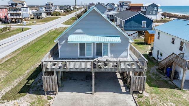 rear view of property with a deck with water view and a carport