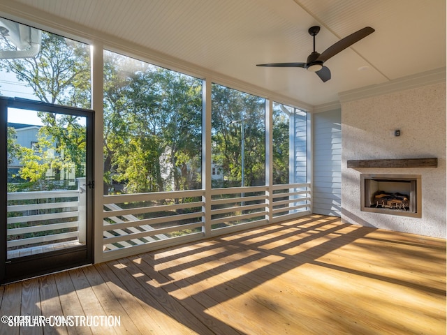 unfurnished sunroom with a ceiling fan and a fireplace