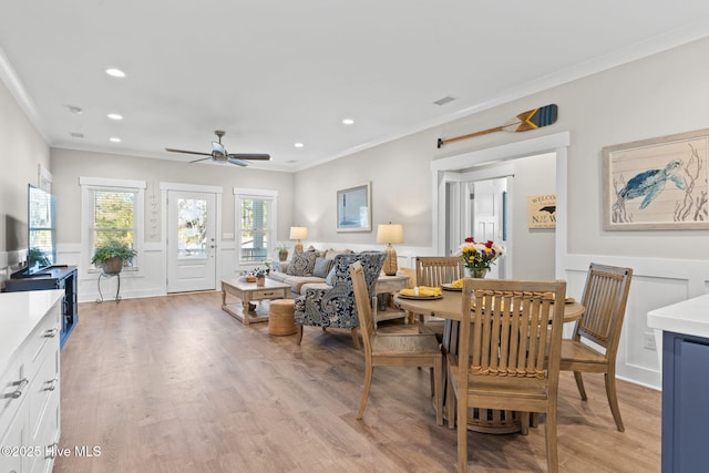 interior space featuring light wood finished floors, crown molding, and a wainscoted wall