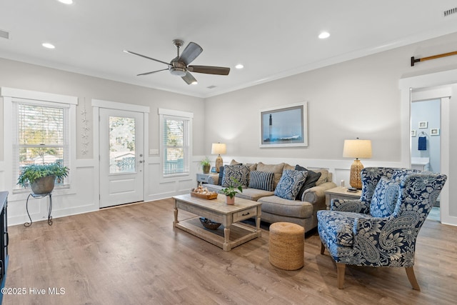 living area featuring recessed lighting, wood finished floors, a ceiling fan, ornamental molding, and wainscoting