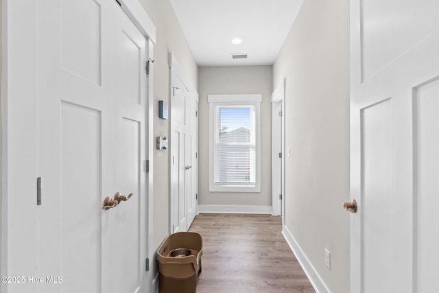 corridor with wood finished floors, visible vents, and baseboards