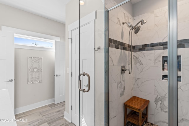 bathroom featuring a stall shower, baseboards, and wood finished floors