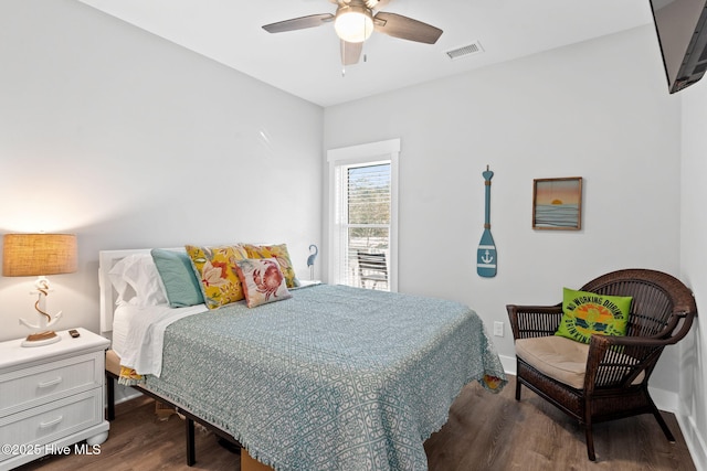 bedroom with a ceiling fan, visible vents, baseboards, and wood finished floors