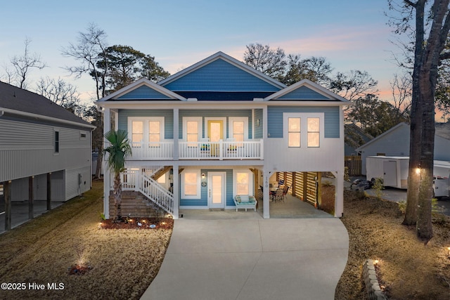 view of front of property with a carport, a porch, stairway, and concrete driveway