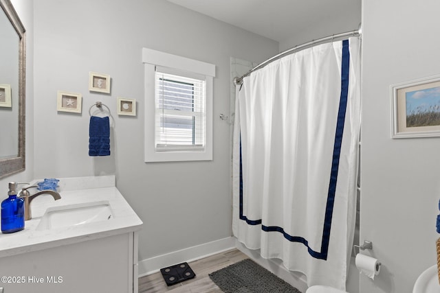 full bath featuring curtained shower, wood finished floors, vanity, and baseboards