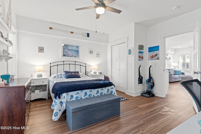 bedroom featuring ceiling fan, a closet, baseboards, and wood finished floors