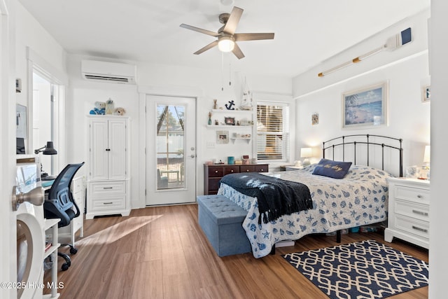 bedroom with access to outside, a wall mounted air conditioner, ceiling fan, and wood finished floors