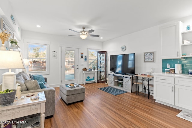 living area featuring light wood-style flooring, baseboards, ceiling fan, and recessed lighting