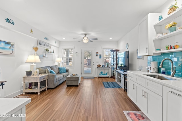 kitchen featuring white cabinets, light wood-style floors, open shelves, and a sink