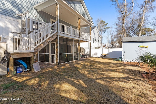 back of house featuring a yard, a sunroom, fence, an outdoor structure, and stairs