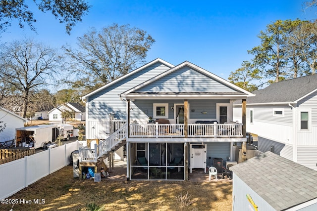 back of property with a sunroom, fence, and stairs