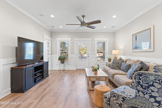 living room featuring a healthy amount of sunlight, light wood-style floors, ornamental molding, and wainscoting