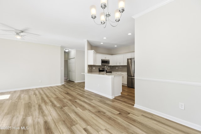 kitchen featuring appliances with stainless steel finishes, ceiling fan with notable chandelier, recessed lighting, open floor plan, and tasteful backsplash